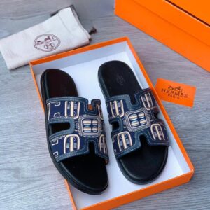 Stylish blue and gold Hermès slides with geometric patterns, perfect for summer or special occasions. Ideal for fashion-forward individuals who appreciate high-end style and comfort.