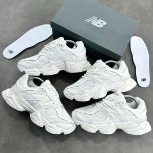 A pair of white New Balance sneakers with a gray shoe box and insoles on a gray background, showcasing the shoe's stylish design and comfortable features.
