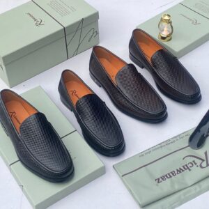 A pair of black woven leather loafers on a shoe box with accessories