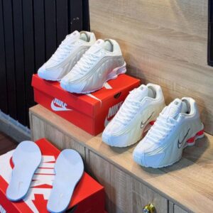 High-end white Nike sneakers displayed on a wooden shelf with red shoe boxes, perfect for luxury fashion enthusiasts in Nigeria.