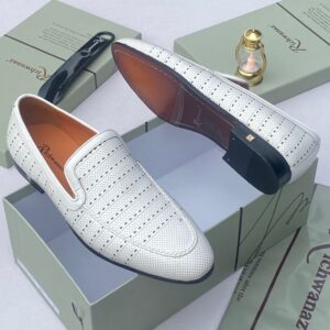 A pair of white perforated leather loafers from Richwanz, displayed on a shoe box with accessories.
