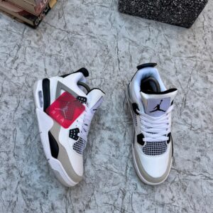 A pair of white, black, and grey Air Jordan 4 Retro sneakers on a marble surface, perfect for sneaker lovers in Nigeria.