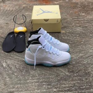High-class Air Jordan 11 Low sneakers in white and blue, displayed with box and accessories on a concrete background, showcasing luxury footwear for the elite in Nigeria.