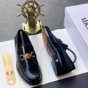 A pair of luxury black leather loafers with a gold buckle, presented on a white shoe box with a shoe horn and a decorative ship's wheel in the background, symbolizing high-class products for the elite at Levonteluxe in Nigeria.