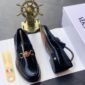 A pair of luxury black leather loafers with a gold buckle, presented on a white shoe box with a shoe horn and a decorative ship's wheel in the background, symbolizing high-class products for the elite at Levonteluxe in Nigeria.