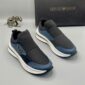 A pair of luxury Emporio Armani black and blue sneakers with white soles, displayed with a silver elephant statue and black box.