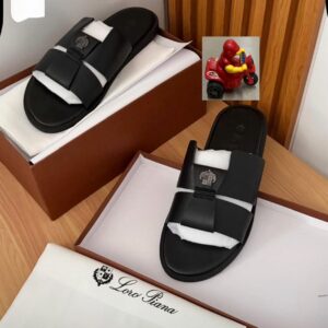A pair of black double strap slide sandals with emblem detailing, nestled in their box, showcasing luxury and high-class design.