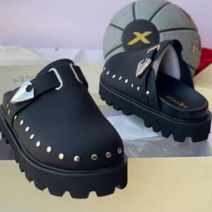 Luxury green half shoes with chunky black sole and stud-adorned upper, presented on a cream-colored shoe box.