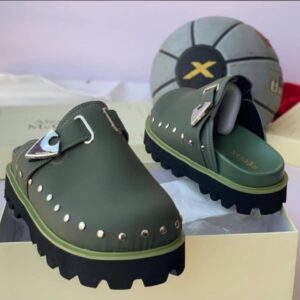 Luxury green half shoes with chunky black sole and stud-adorned upper, presented on a cream-colored shoe box.