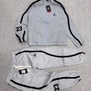 A luxurious black tracksuit with grey stripes and Nike logo, laid out on a grey surface, exuding high-end quality and style.