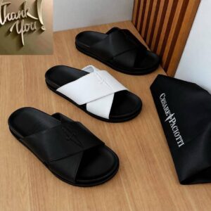 Luxurious slides in black and white, presented on a wooden table with a black bag bearing the Cesare Paciotti logo, exuding high-end quality and sophistication.