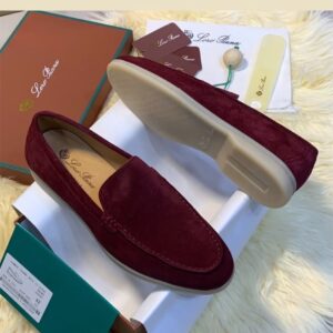 A pair of luxurious maroon loafers with cream-colored soles, nestled in their elegant box and accompanied by premium accessories.